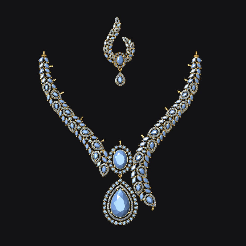An ornate gold-toned jewelry set featuring a V-shaped necklace and a matching topkara earring, both adorned with small clear stones and a central teardrop-shaped light blue gemstone, set against a solid black background.