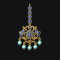 Decorative gold pendant with blue and green gemstones on a black background