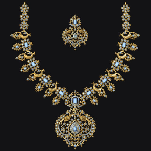An ornate gold-toned jewelry set featuring a necklace and matching earrings, embellished with light blue stones and small clear stones, displayed on a solid black background.