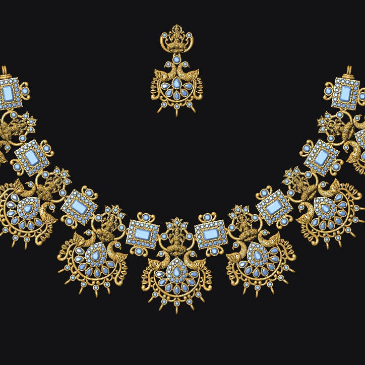 An ornate gold necklace with matching crown and connector piece, decorated with light blue and white stones, displayed on a solid black background.