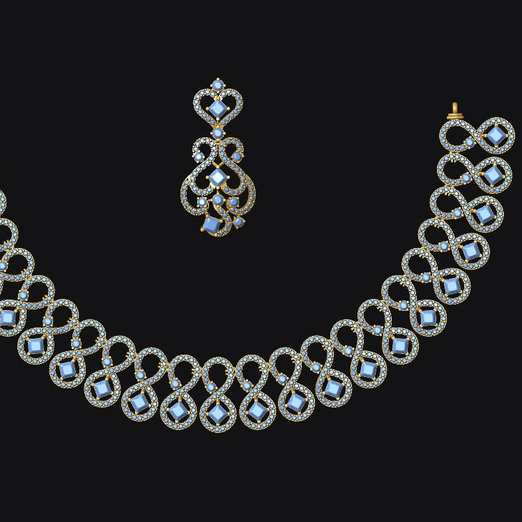 Gold-toned jewelry set featuring an ornate necklace and matching drop earring, both decorated with small clear stones and light blue faceted gemstones, shown on a solid black background.