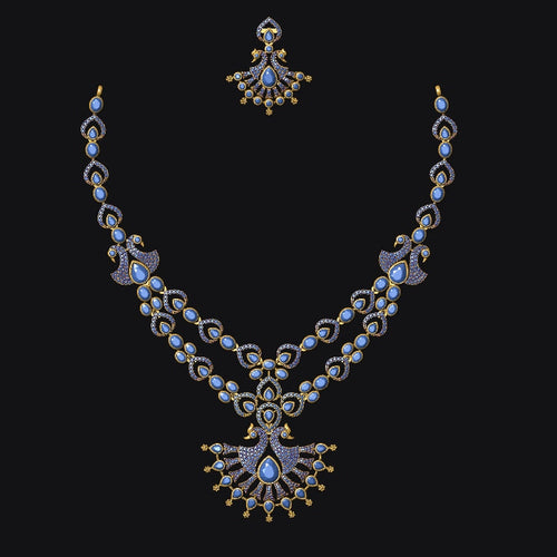 An ornate gold-toned double-strand necklace with a matching stud earring, featuring light blue stones and gold accents, displayed against a solid black background.